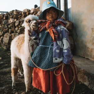 eSIM Bolivia girl wearing multicolored dress standing near white llama