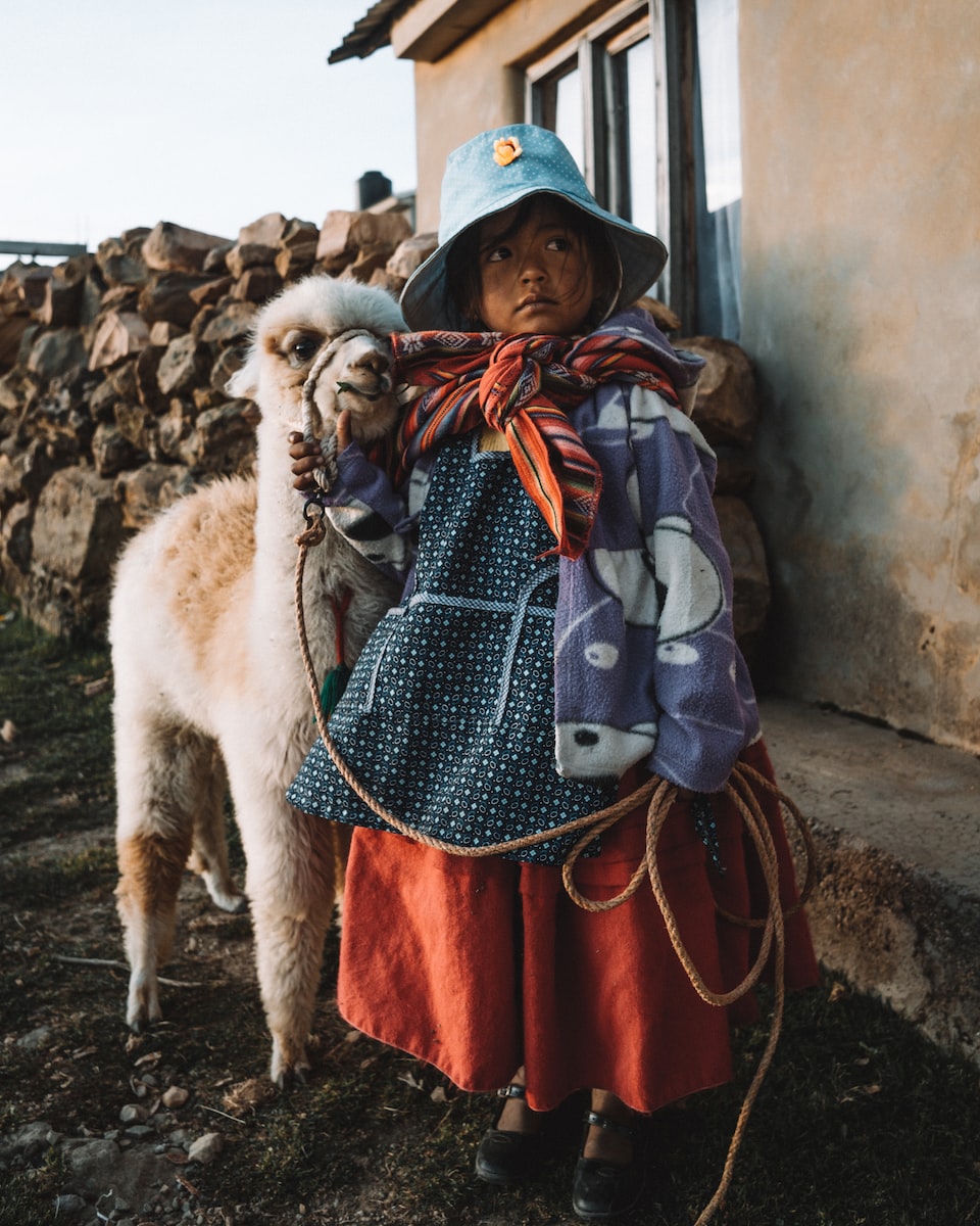 eSIM Bolivia girl wearing multicolored dress standing near white llama
