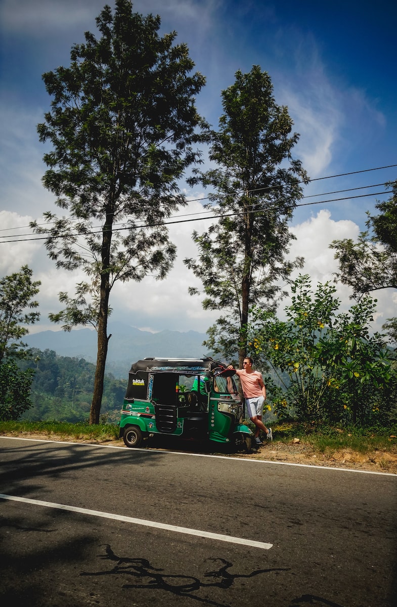 man in green jacket riding green and black auto rickshaw on road during daytime