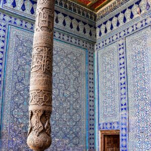 a pillar in front of a wall with a design on it