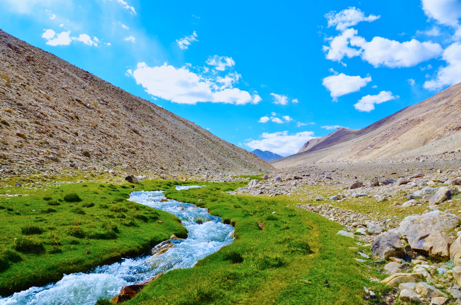 river in between brown mountains under blue sky during daytime